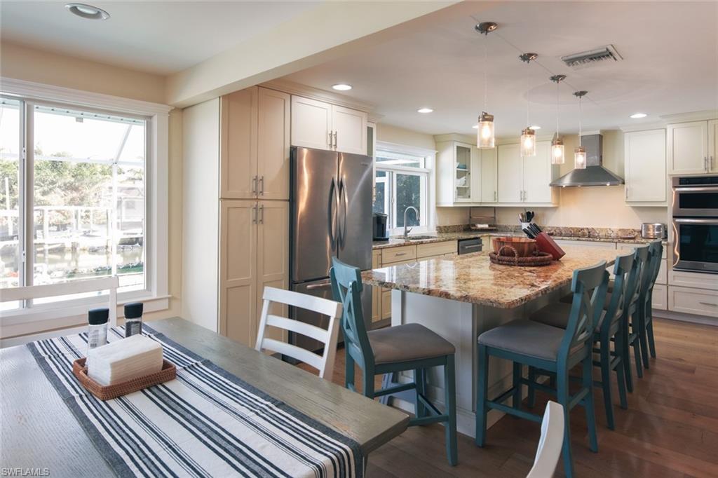 2155 Tarpon Road Naples, FL 34102 - Photo 10 of 27 a dining room with stainless steel appliances granite countertop furniture a couch a stove a kitchen island with a dining table and chairs