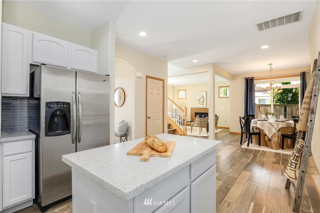 4408 Northeast 3rd Lane Renton, WA 98059 - Photo 10 of 25 a open kitchen with stainless steel appliances kitchen island granite countertop a refrigerator a stove and white cabinets with wooden floor