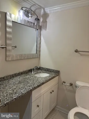a bathroom with a granite countertop sink toilet and a mirror