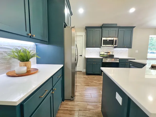 a kitchen with stainless steel appliances kitchen island granite countertop a refrigerator a stove and a sink with wooden floor