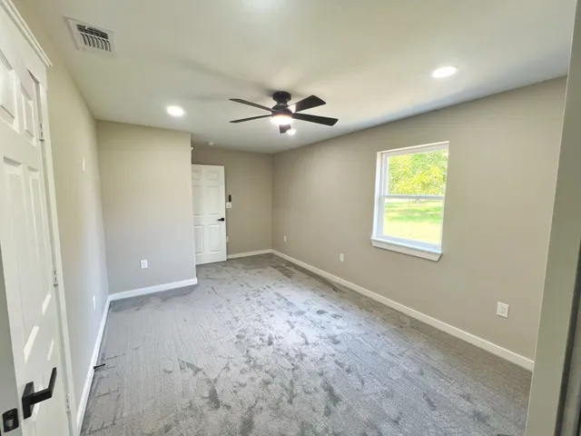 an empty room with a ceiling fan and a window