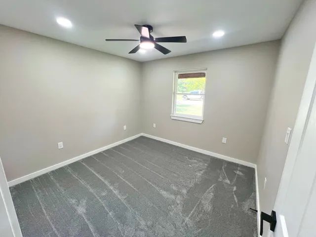 an empty room with a ceiling fan and window