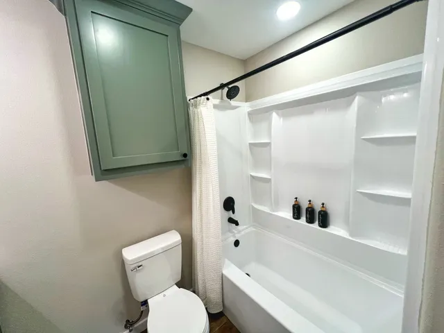 a white toilet sitting next to a bathroom sink and tub