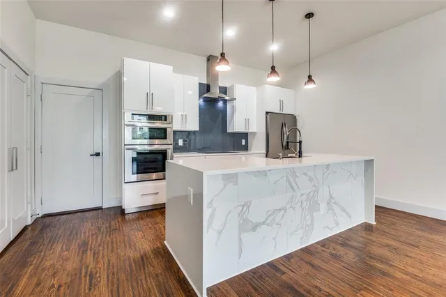 a kitchen with stainless steel appliances a refrigerator a sink a center island and wooden floor