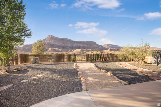 1440 West 100 South Virgin, UT 84779 - Photo 35 of 45 Expansive desert landscaping featuring gravel and stone pathways, a wood-slat perimeter fence, and a distant mountain backdrop