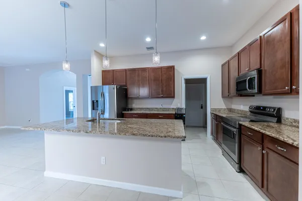a large kitchen with stainless steel appliances kitchen island granite countertop a stove a sink a microwave and a refrigerator