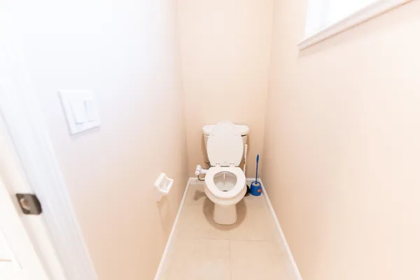 a white toilet sitting next to a white wall