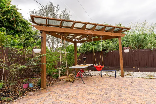 a view of patio with a table and chairs under an umbrella with a small yard