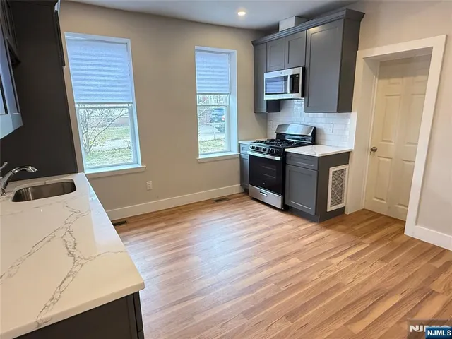 a kitchen with granite countertop a stove top oven a sink and a microwave