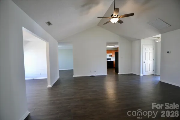 a view of an empty room with window and wooden floor