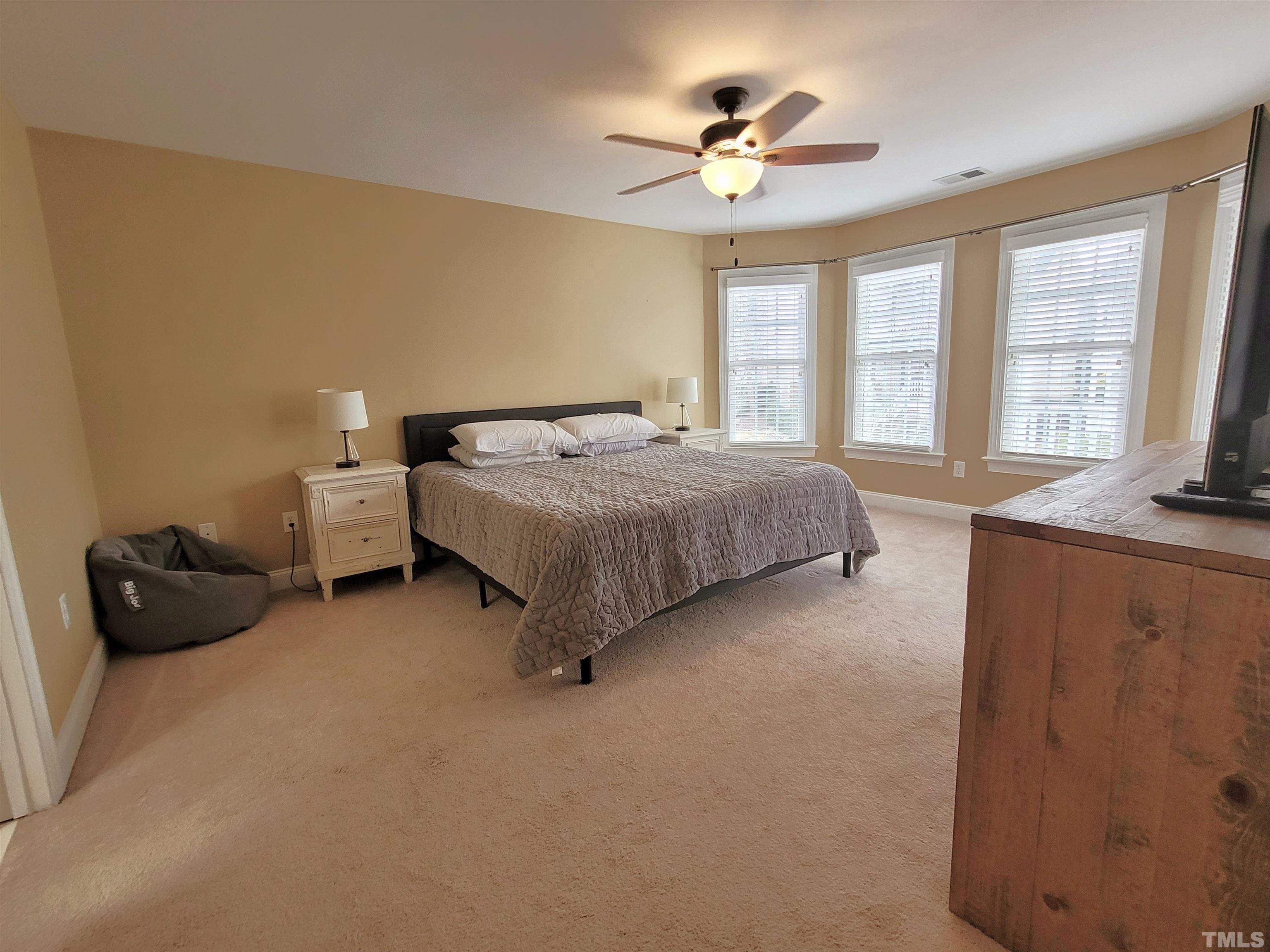 411 Magdala Place Apex, NC 27502 - Photo 15 of 29 a spacious bedroom with a bed and a chandelier