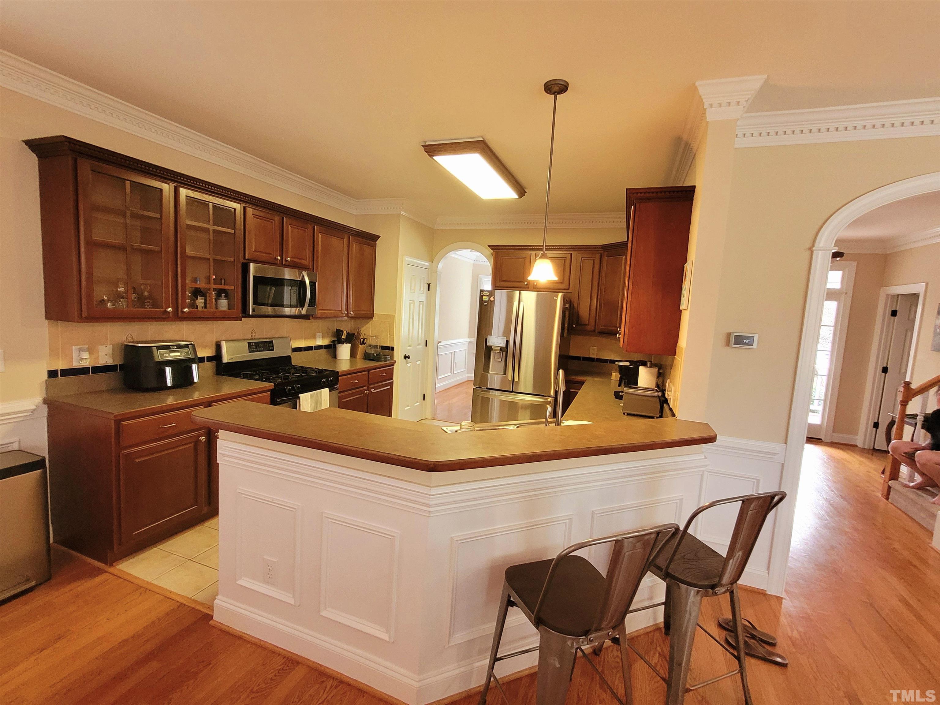 411 Magdala Place Apex, NC 27502 - Photo 19 of 29 a kitchen with stainless steel appliances granite countertop a stove top oven a sink a dining table and chairs with wooden floor
