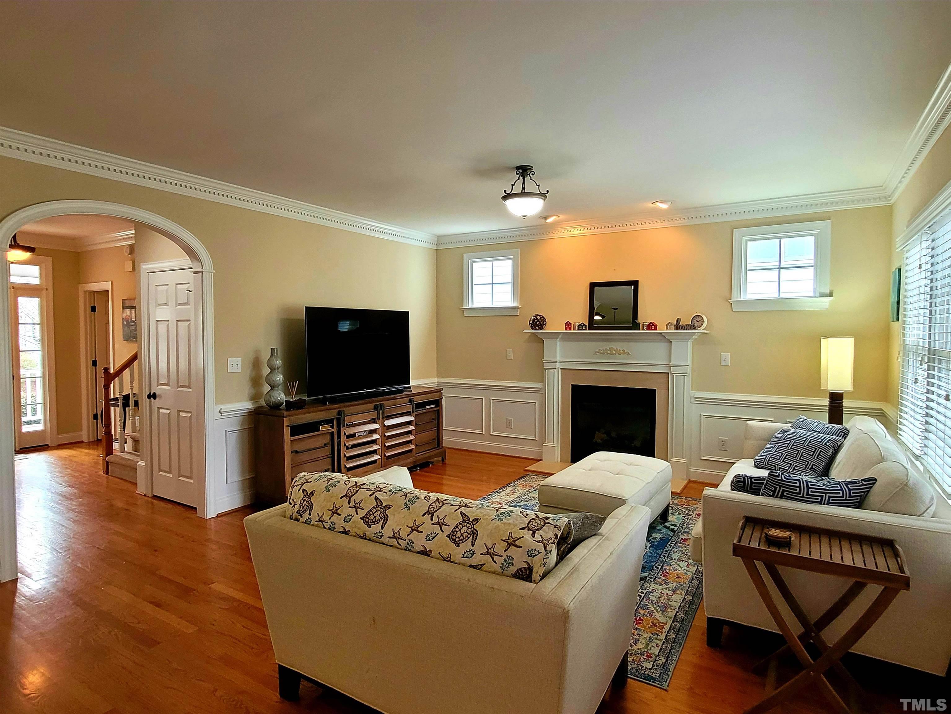 411 Magdala Place Apex, NC 27502 - Photo 26 of 29 a living room with furniture a flat screen tv and a fireplace