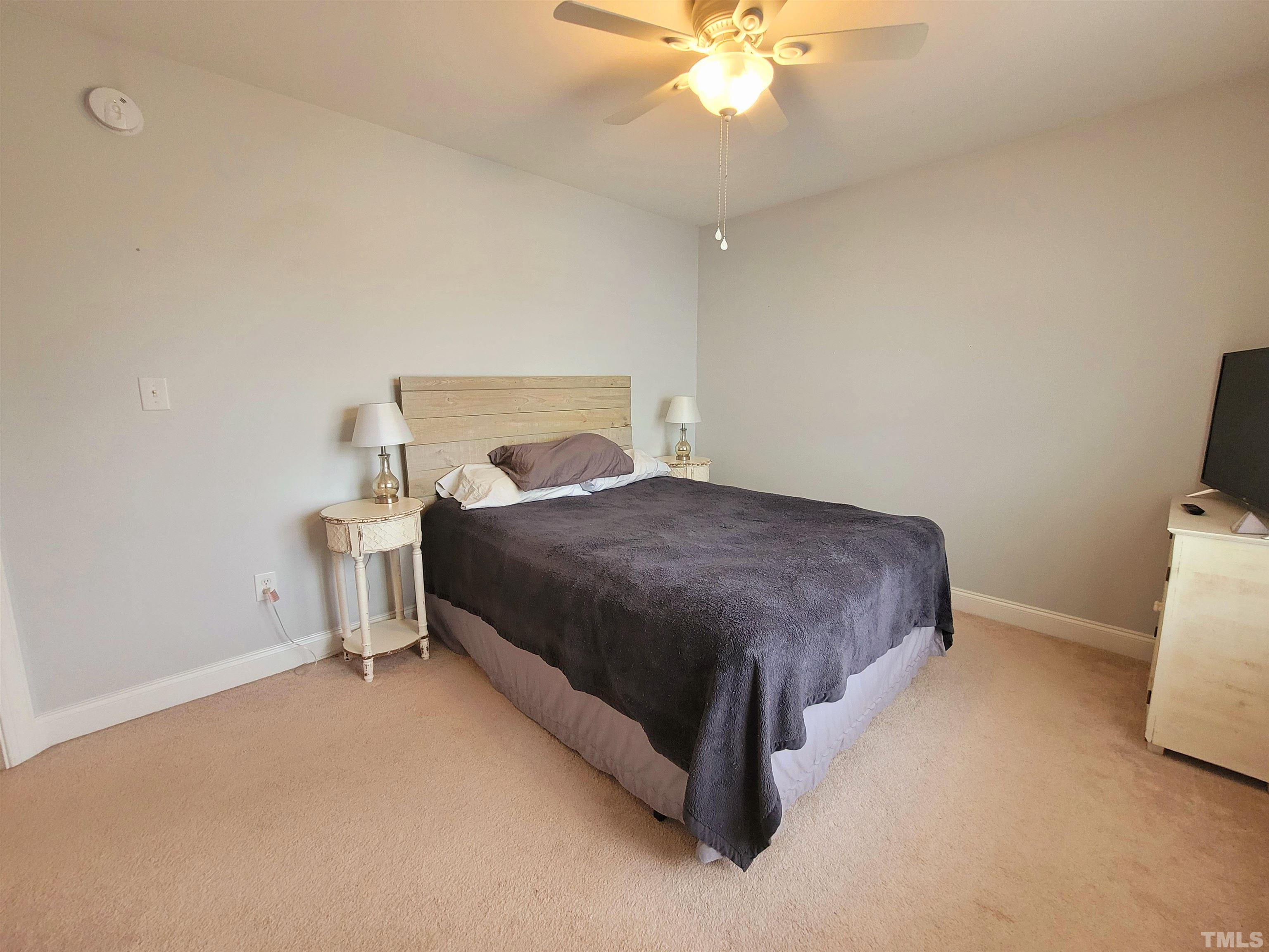 411 Magdala Place Apex, NC 27502 - Photo 9 of 29 a spacious bedroom with a bed and a chandelier