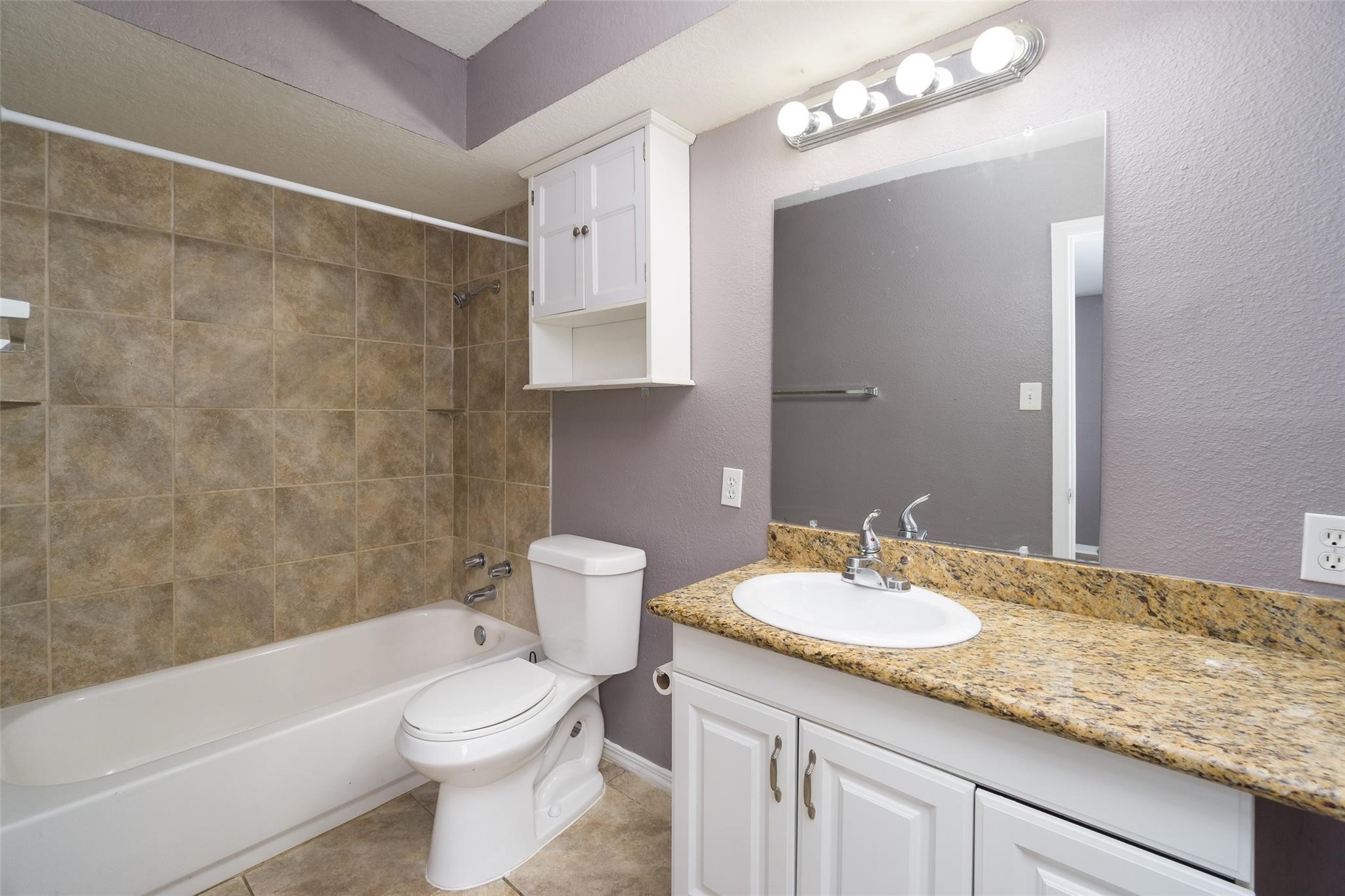 4604 South Tower Road Santa Fe, TX 77517 - Photo 14 of 28 a bathroom with a granite countertop sink a toilet a mirror and bathtub