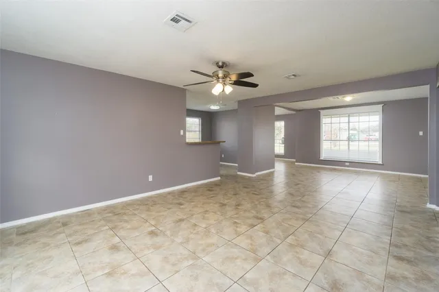 a view of an empty room with window and chandelier fan