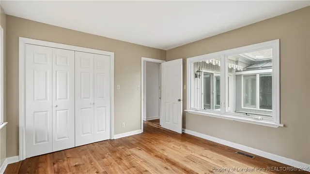 a view of an empty room with wooden floor and a window