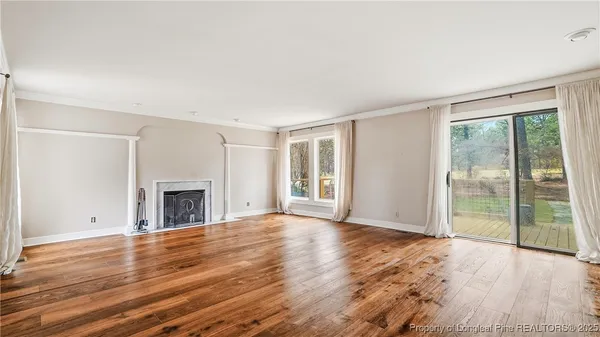 a view of empty room with wooden floor and fireplace