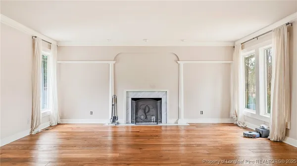 a view of empty room with wooden floor and fireplace