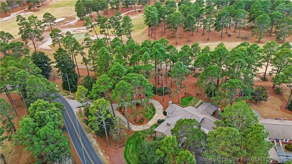 an aerial view of residential house with outdoor space and trees all around