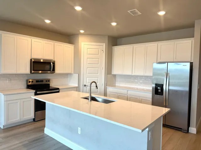 a kitchen with stainless steel appliances granite countertop a sink a stove a refrigerator with grey cabinets