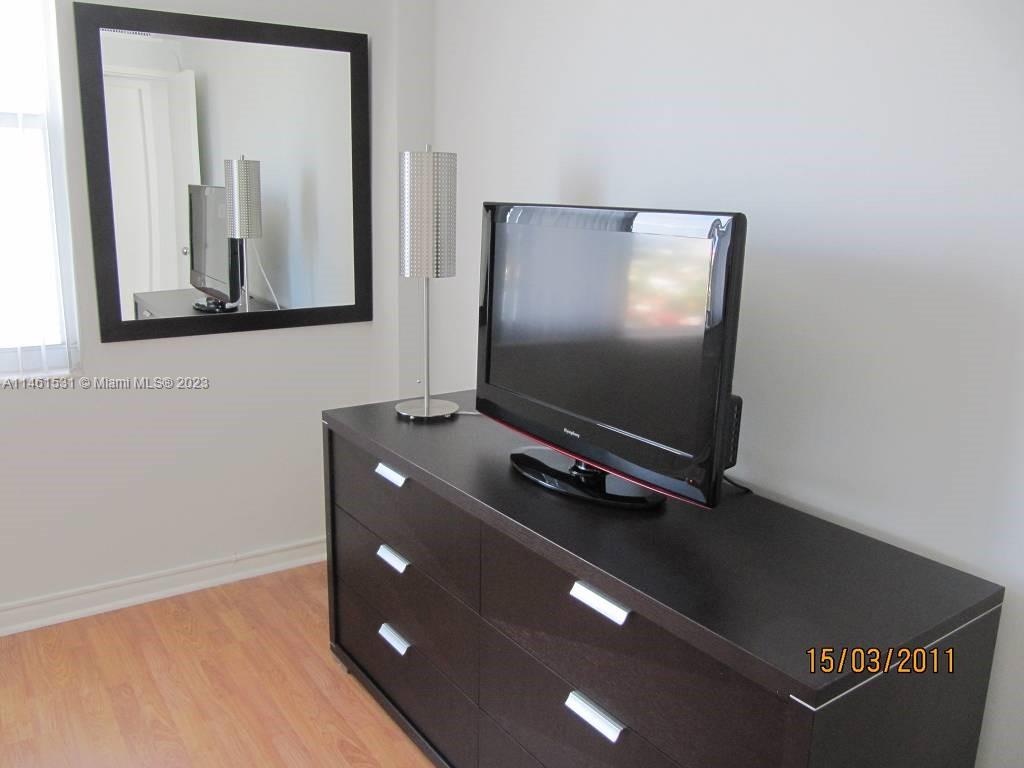 9195 Collins Avenue, Unit 613 Surfside, FL 33154 - Photo 3 of 13 a living room with a flat screen tv and gym equipment