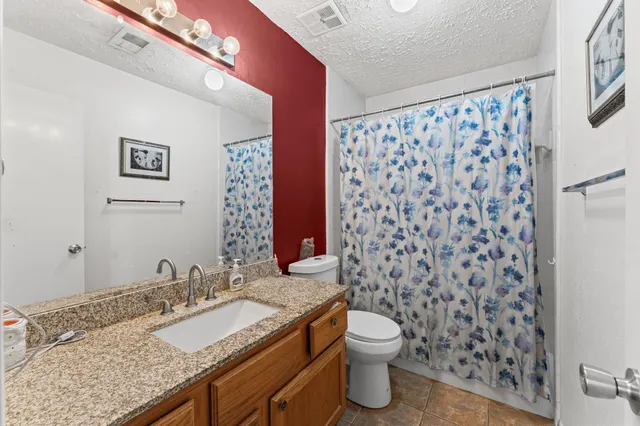 a bathroom with a granite countertop sink toilet and shower