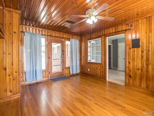 a view of empty room with wooden floor and fan