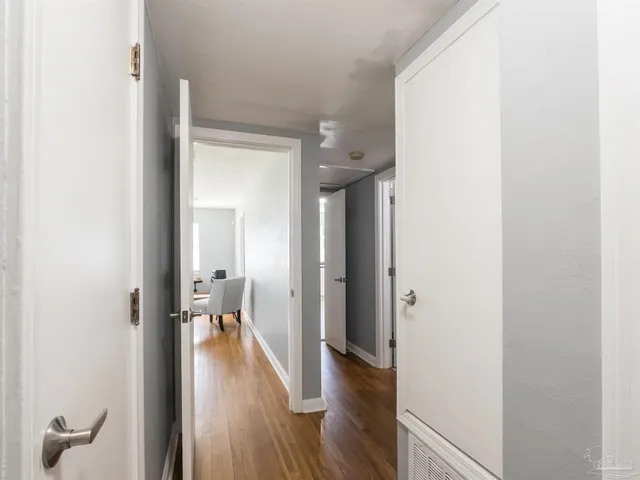 a view of a hallway with wooden floor and a bathroom