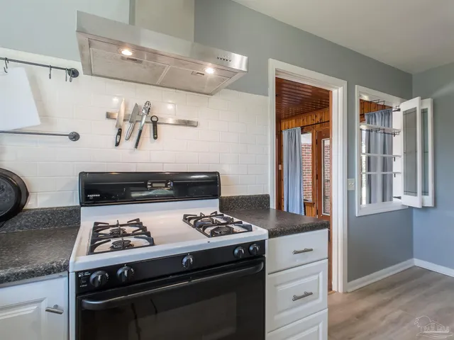 a kitchen with a stove and wooden floor