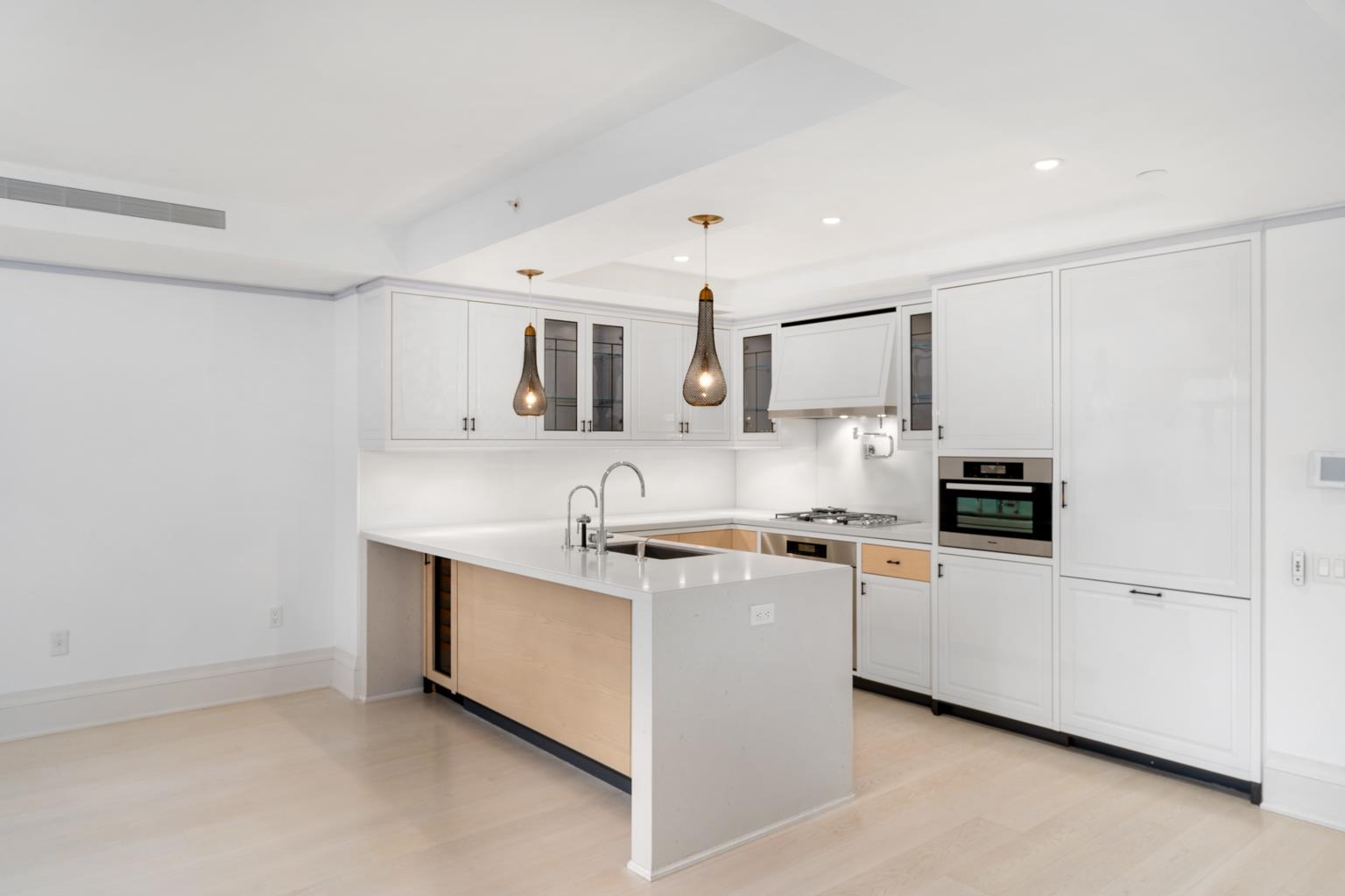 21 East 61st Street, Unit 9C Manhattan, NY 10065 - Photo 7 of 19 a kitchen with stainless steel appliances a sink a stove a microwave a refrigerator a white cabinets and wooden floor