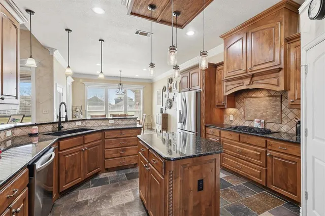 a kitchen with kitchen island granite countertop a sink stove and refrigerator