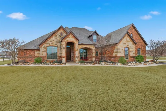 a front view of a house with a garden and lake view