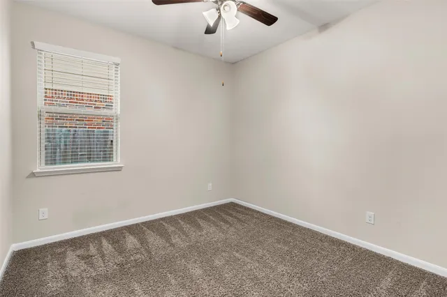 an empty room with a window and a chandelier fan