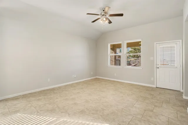 an empty room with windows and ceiling fan