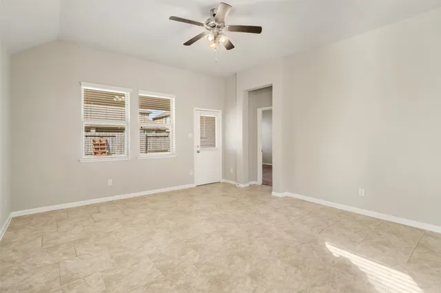 an empty room with windows and ceiling fan