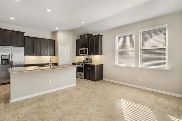 a kitchen with stainless steel appliances granite countertop a stove a sink and a refrigerator