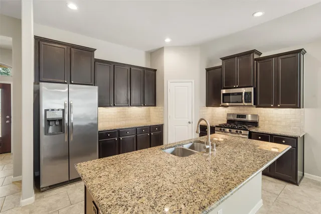 a kitchen with kitchen island granite countertop wooden cabinets a refrigerator and a sink