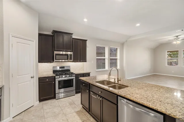 a kitchen with stainless steel appliances granite countertop a sink stove and refrigerator