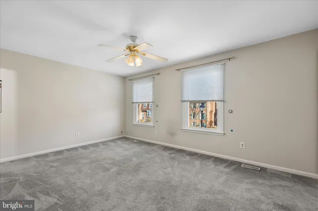 an empty room with windows and chandelier fan