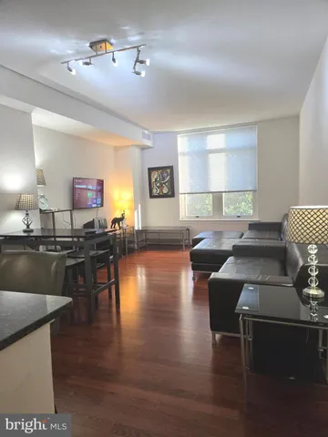 a living room with furniture a lamp and wooden floor