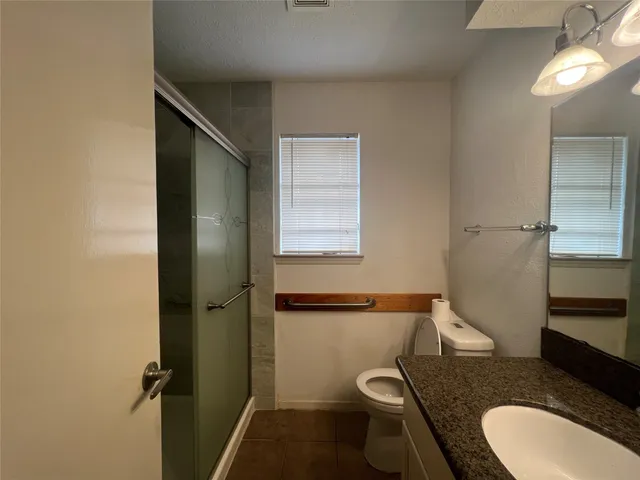 a bathroom with a granite countertop toilet sink and mirror