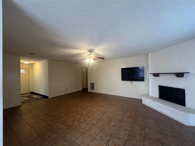 an empty room with windows fireplace and a television