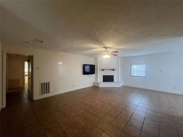 an empty room with windows and fireplace