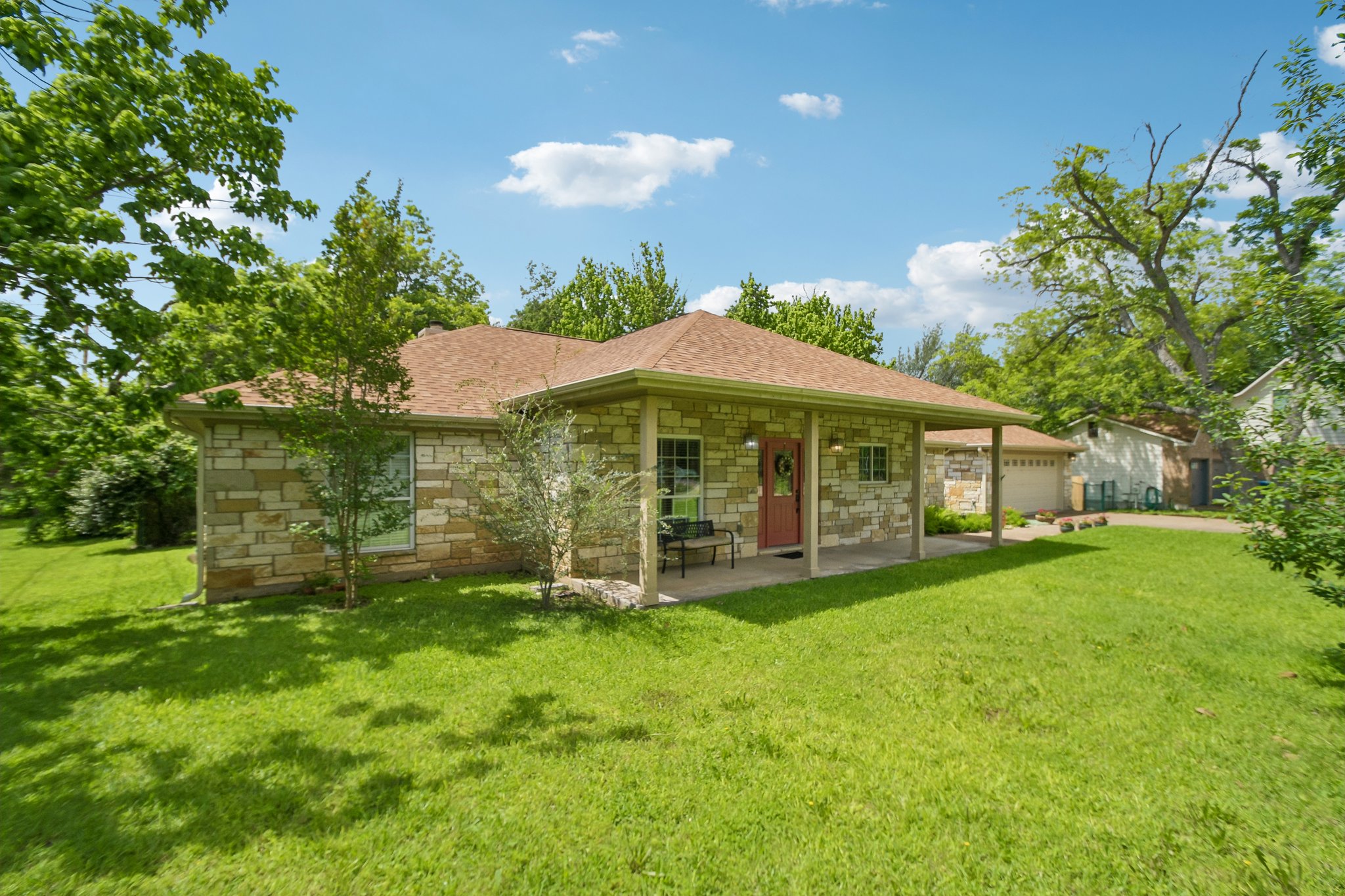 307 West 4th Street Elgin, TX 78621 - Photo 2 of 40 Stone veneer exterior with a covered front porch, a red entry door, and a brown shingle roof