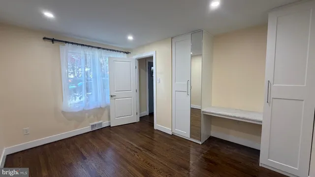 a view of an empty room with wooden floor and closet