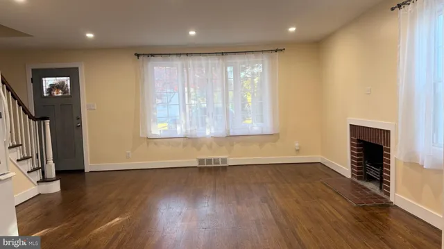 an empty room with wooden floor and a fireplace