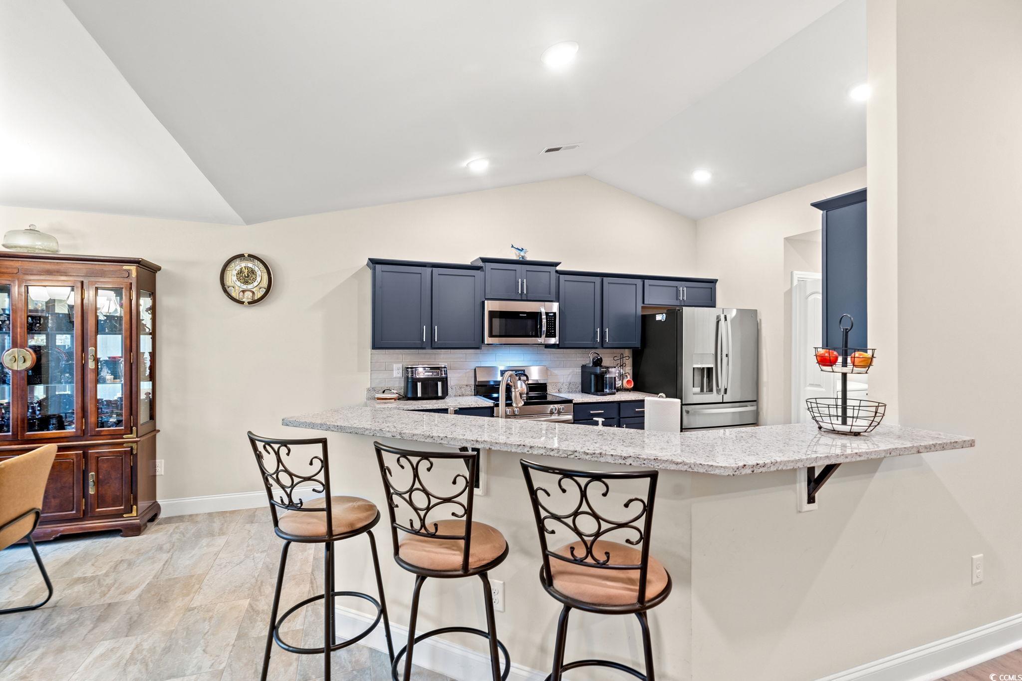 1209 Wehler Court Conway, SC 29526 - Photo 7 of 32 Kitchen featuring a kitchen breakfast bar, lofted ceiling, light stone countertops, a peninsula, and backsplash
