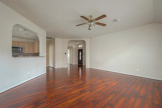 an empty room with wooden floor and windows