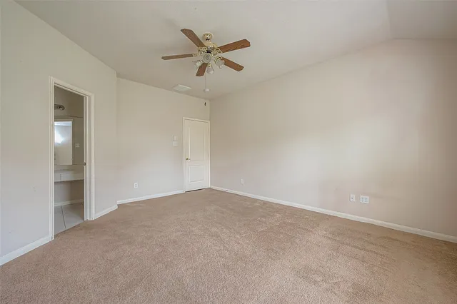 an empty room with a chandelier fan and windows